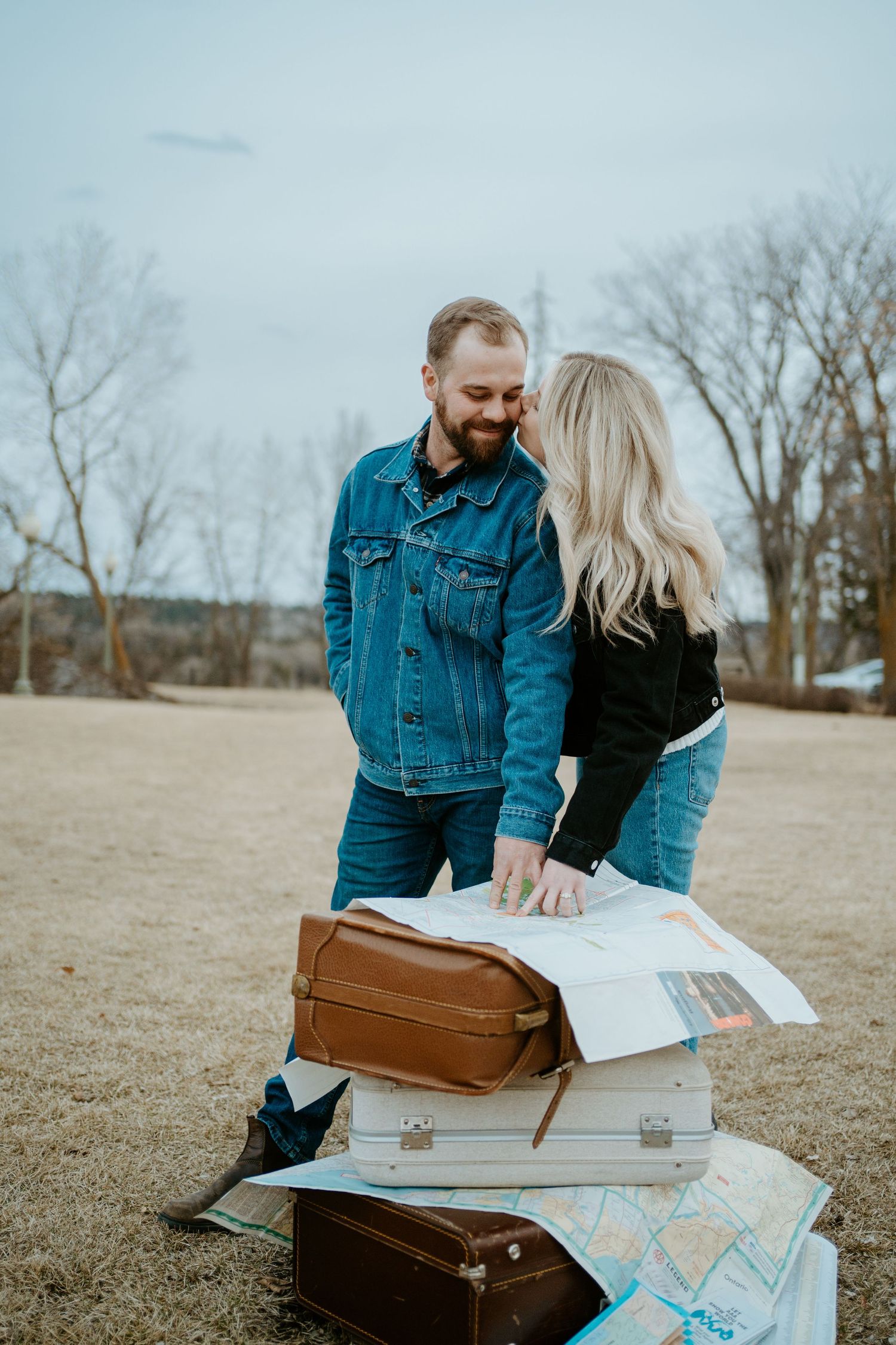 Travel couple looking at maps and vintage suitcases during outdoor adventure planning session.