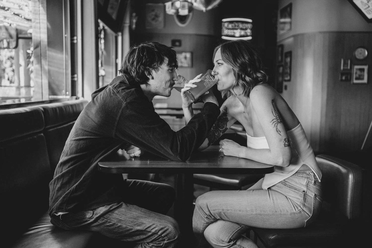Black and white photo of a romantic couple sharing an intimate moment at a diner booth table.