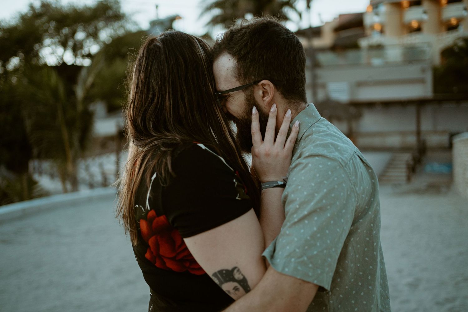 Intimate sunset portrait of couple sharing tender moment on tropical beach.