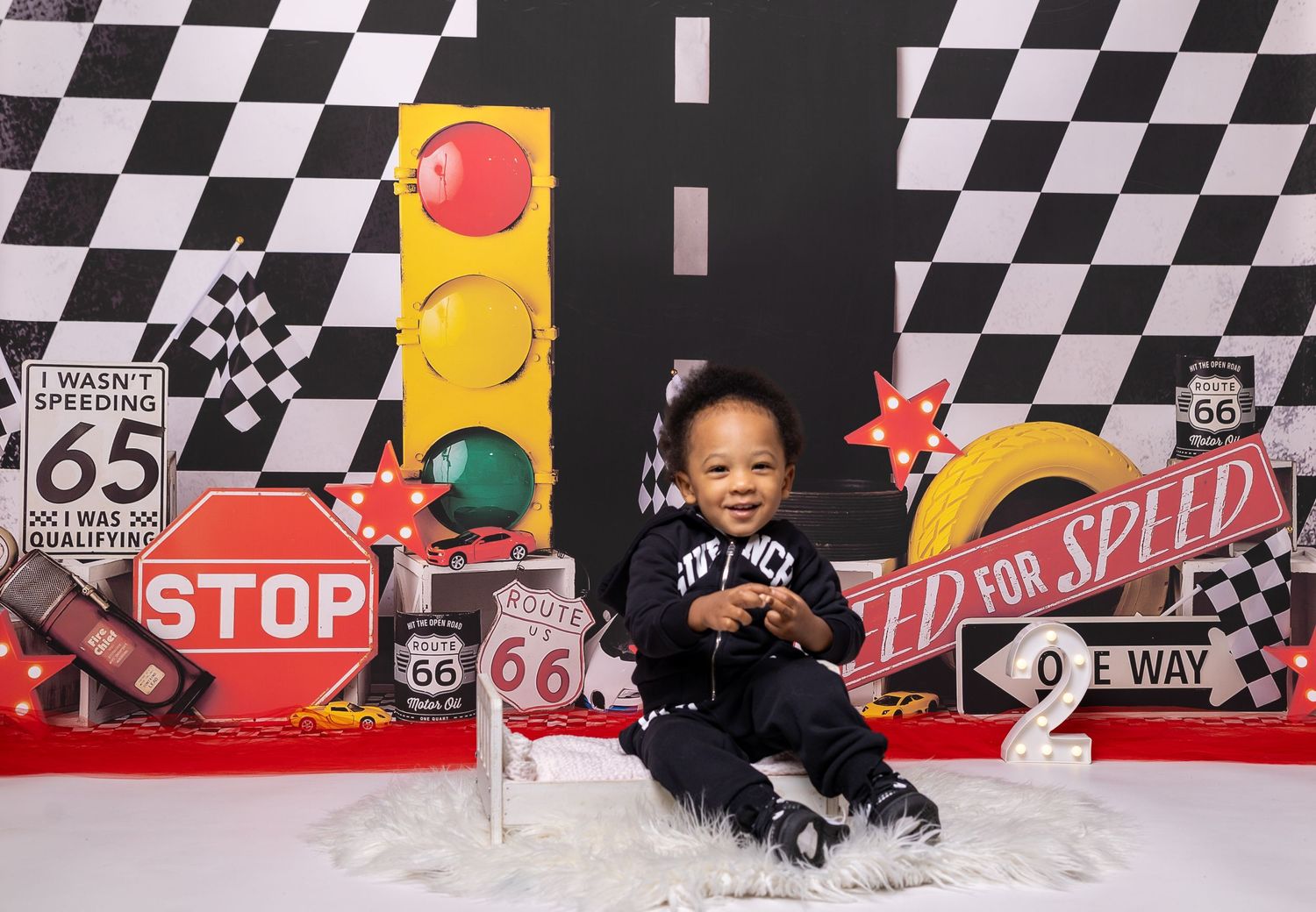 Baby during 2 Fast Cars-inspired milestone session in Glenview IL studio featuring race cars, checkered flags, and road-themed decor.