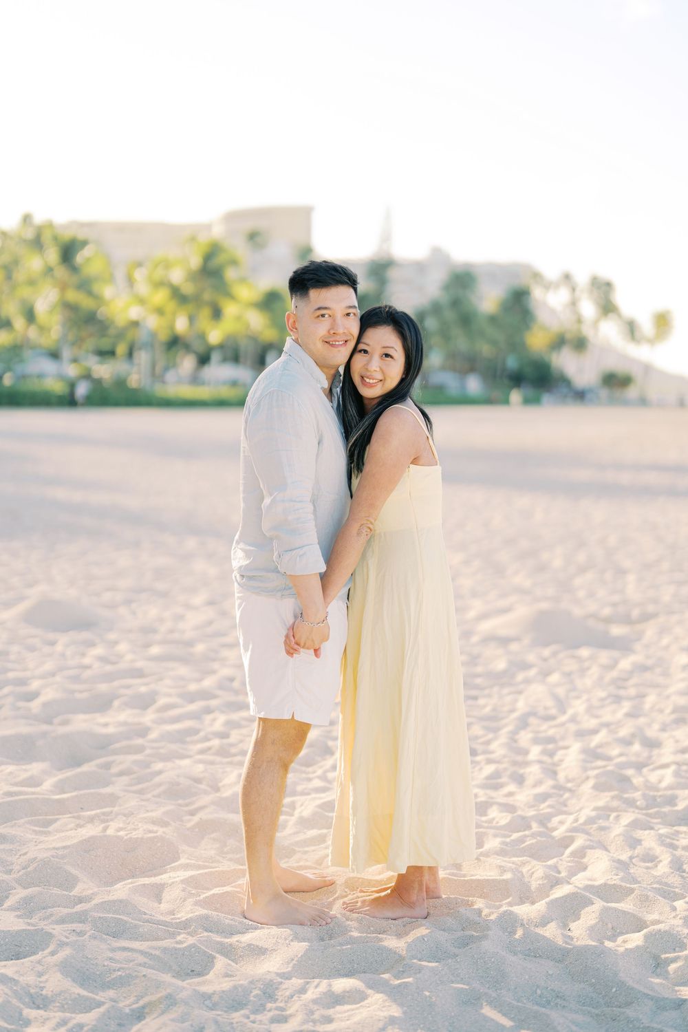 A couple shares tender moments together on a sandy beach during a romantic sunset photo session.