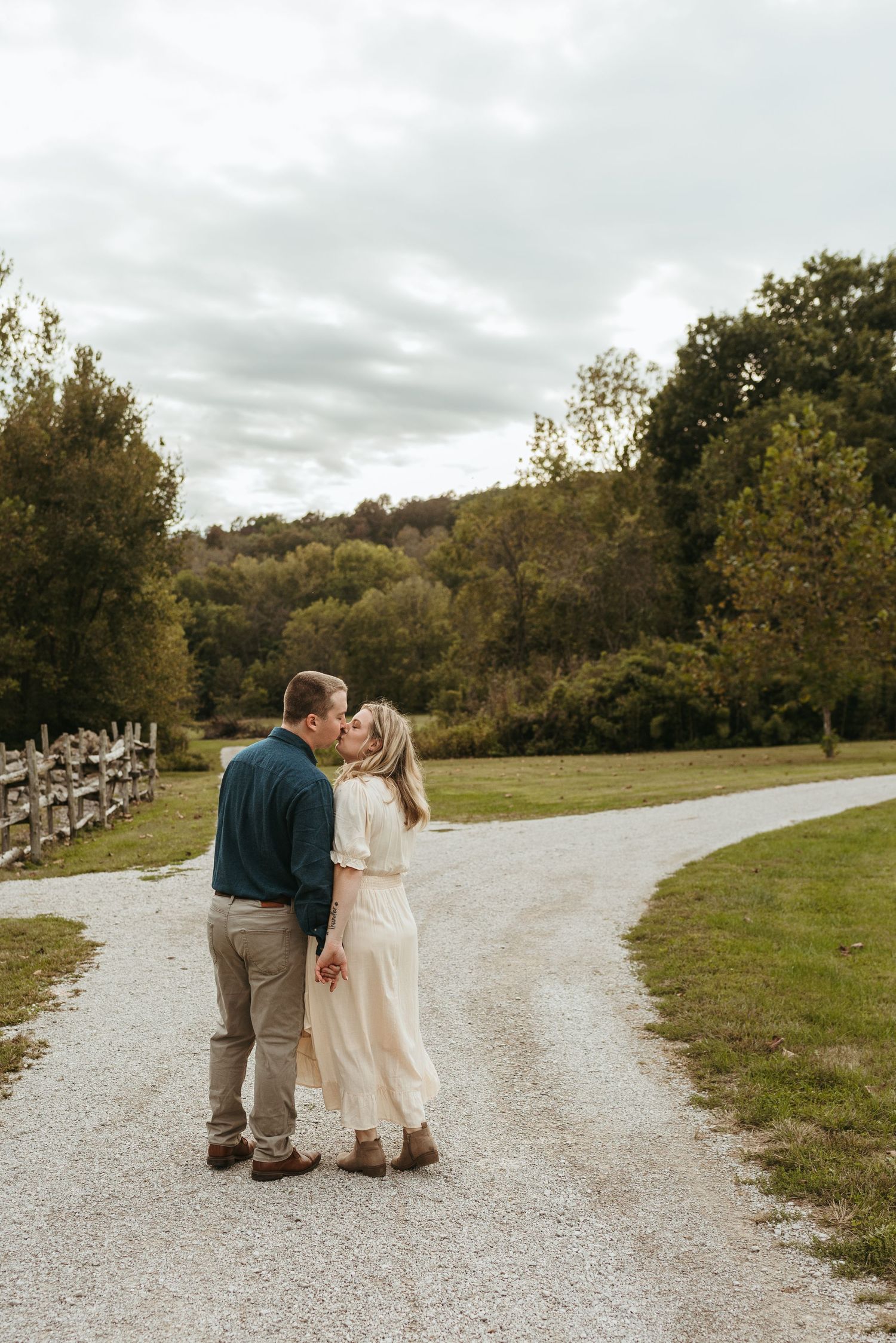 Couple walking together on a winding gravel path through a scenic countryside setting.