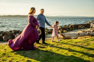 Family enjoying a sunset moment together on rocky coastal cliffs with golden light streaming across green grass.