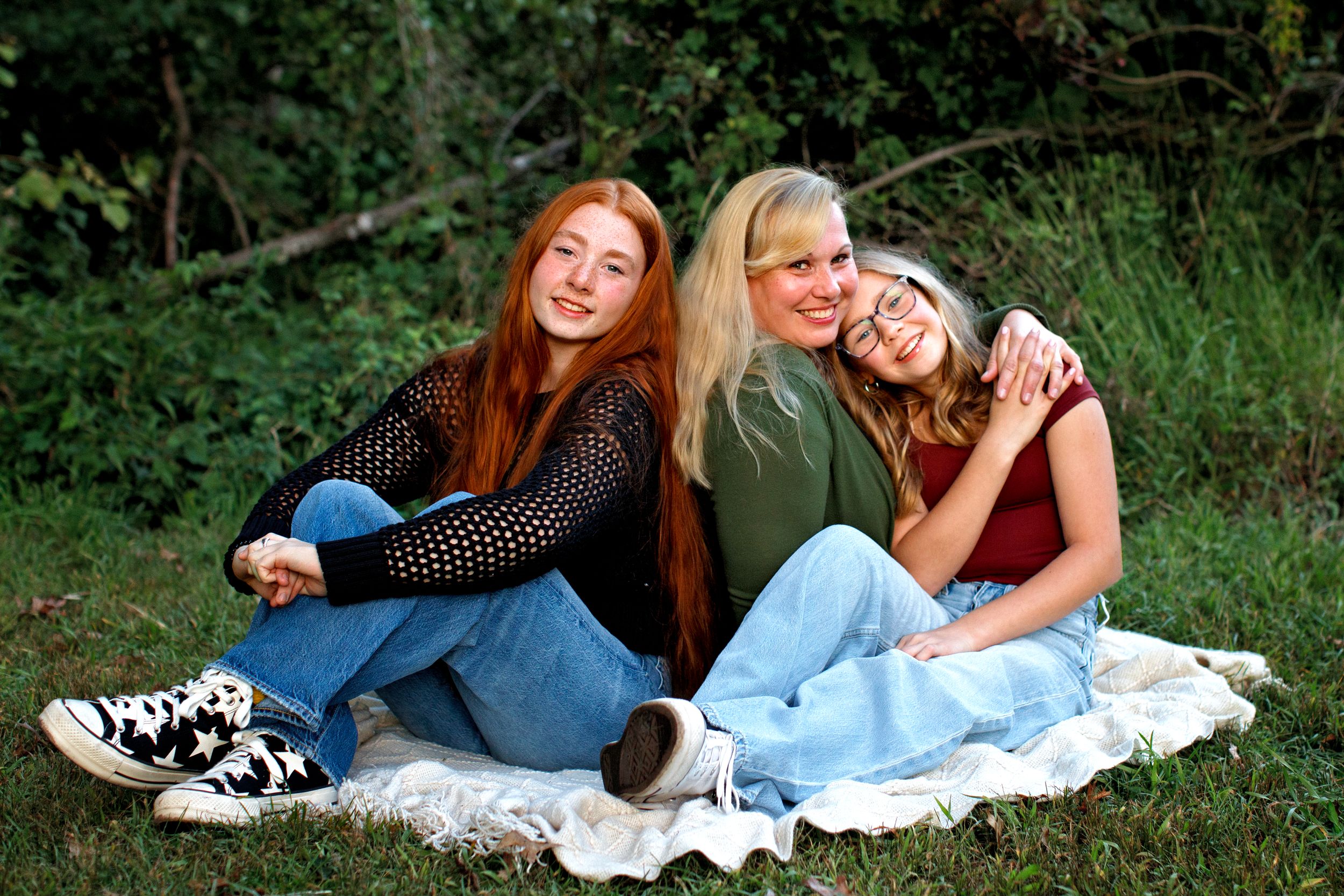 Bergen County photographer mini session loving shot of a family on a blanket in the park near HoHoKus, NJ.  Mom is hugging one of the kids.