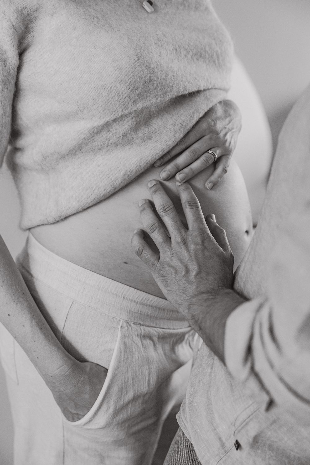 Detail van zwangere buik met hand van partner