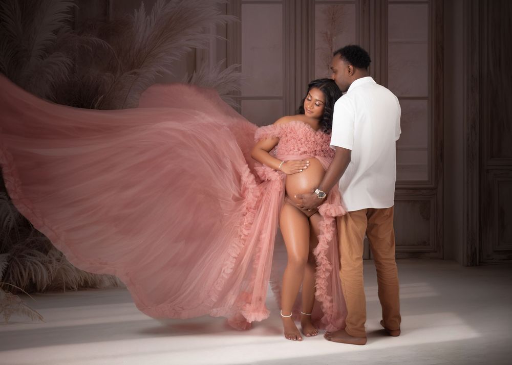 Professional dance duo performs dramatic movement sequence in pink flowing gown against neutral studio backdrop.