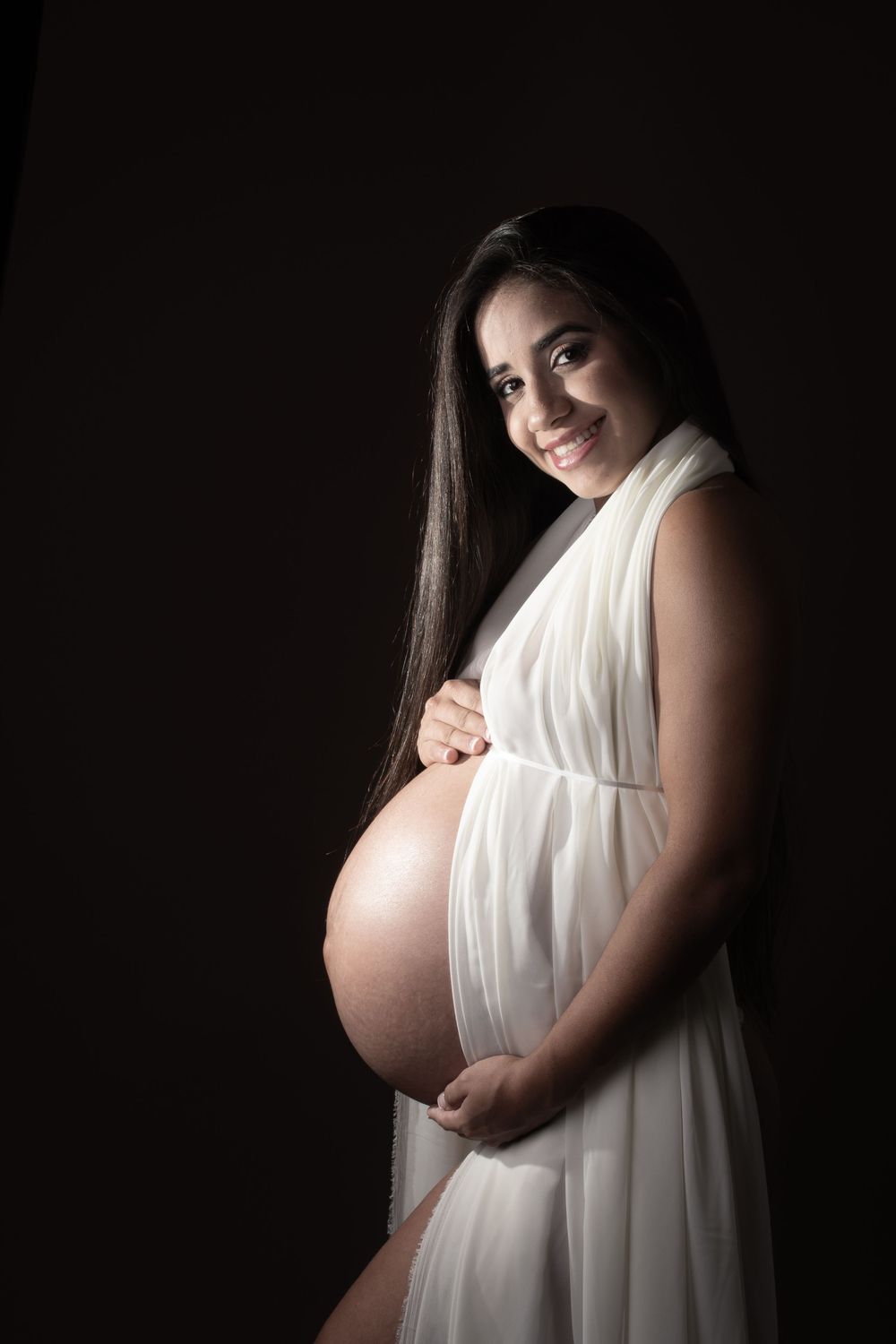 A sequence of maternity silhouette photos showing a pregnant figure in white fabric against a dark background.