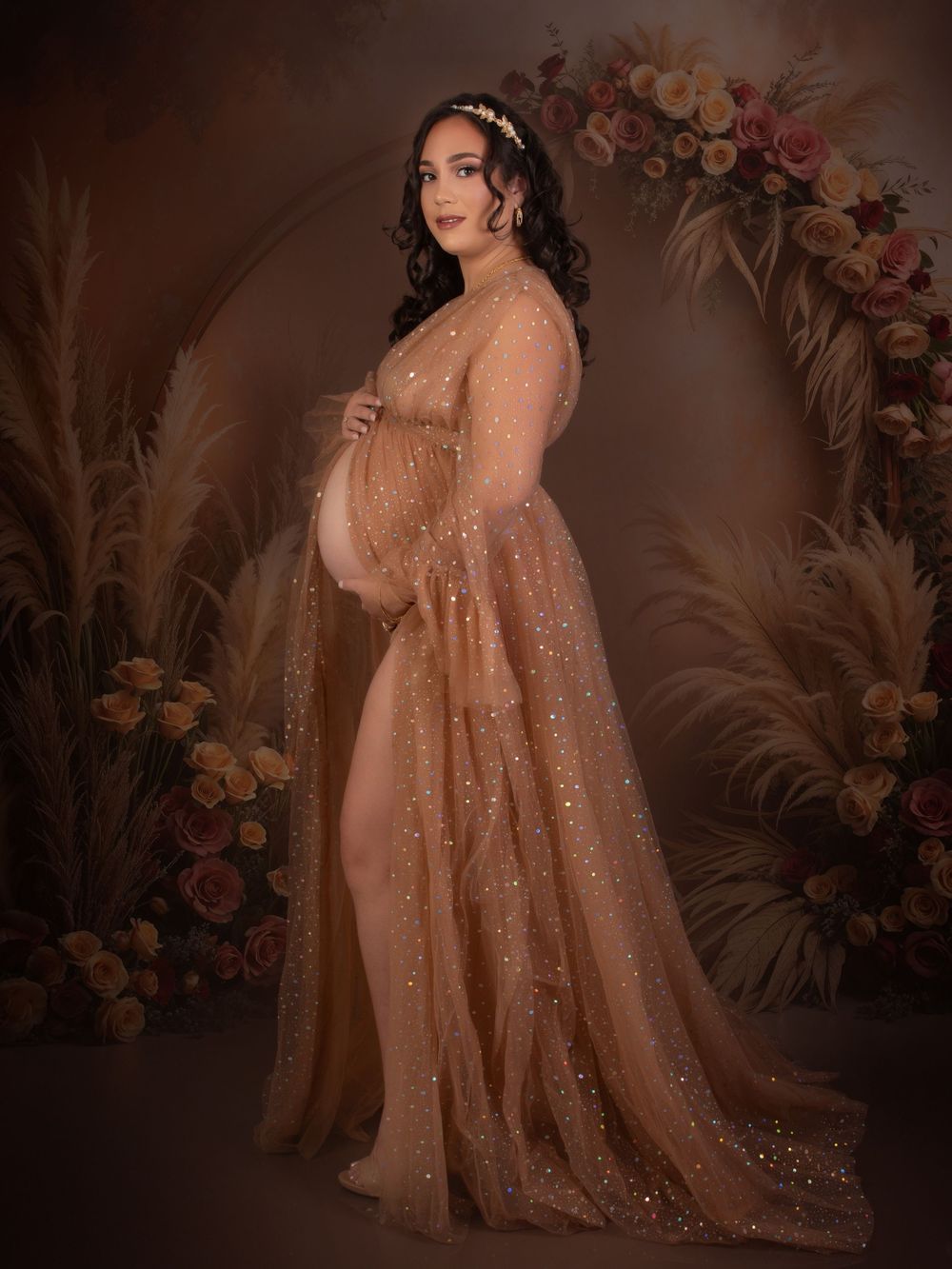 Maternity photos featuring sparkly champagne gown in floral studio setting.