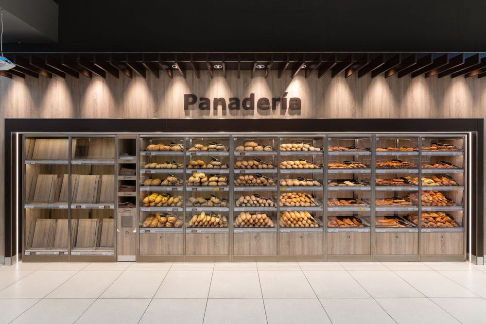 Modern bakery display case with illuminated 'Panaderia' signage showing fresh bread products.