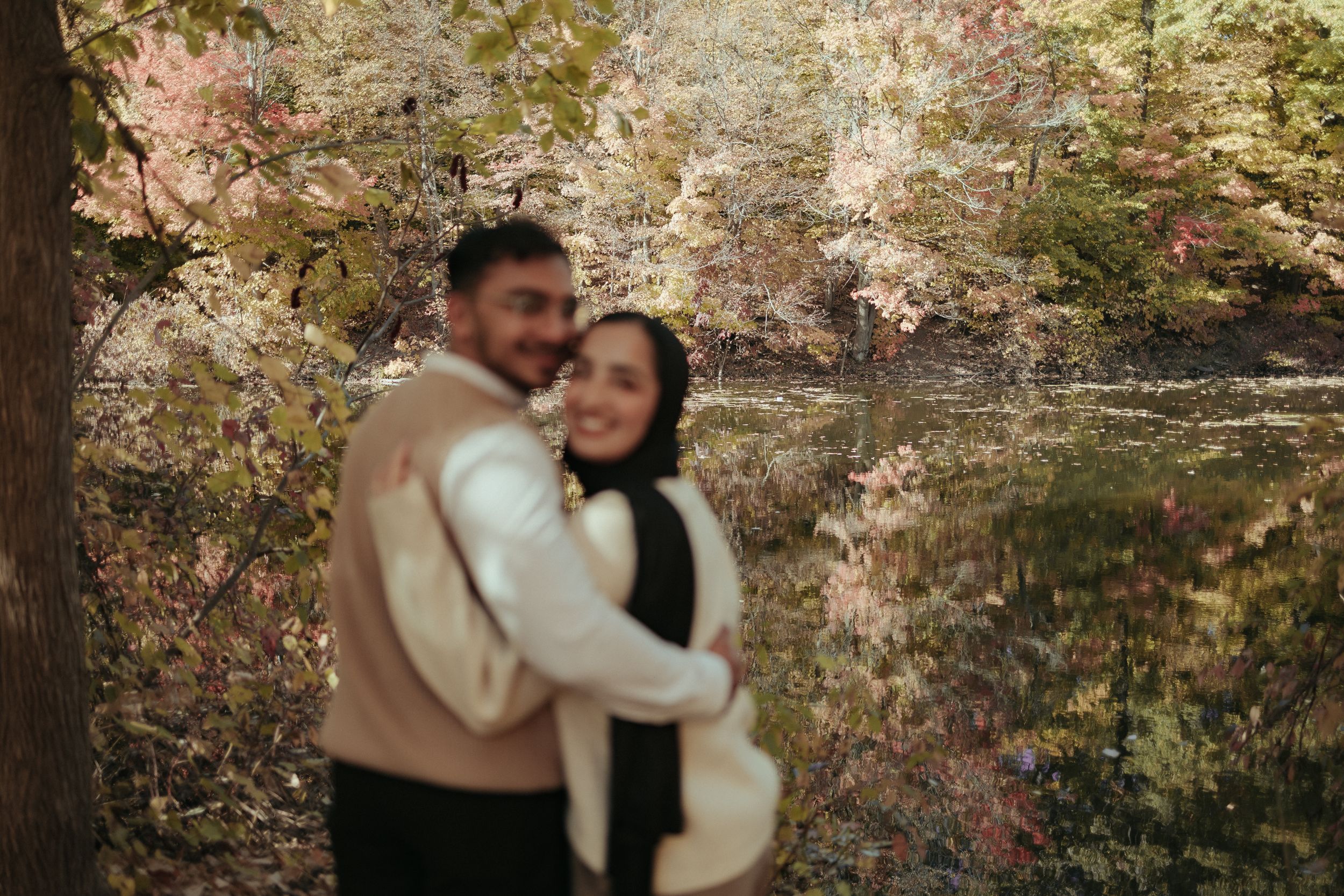Intimate portrait of couple embracing in autumn forest setting.