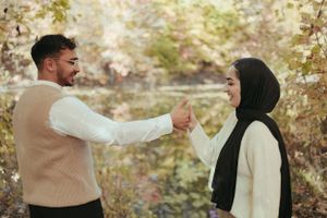 Couple in matching neutral tones sharing playful moment in fall foliage.