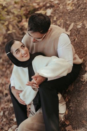 A couple shares an intimate moment outdoors wearing matching white and beige sweaters.