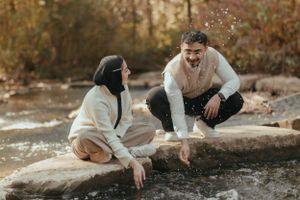 A playful moment captured by a stream as couple sits on rocks.