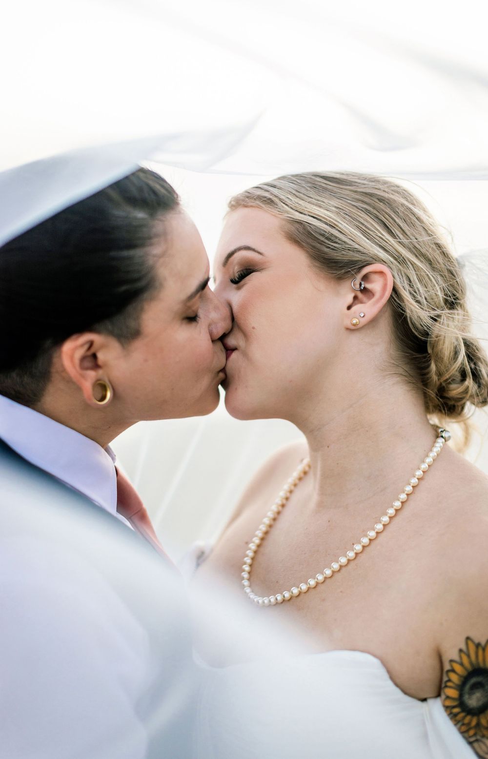 Close-up shots of couple sharing tender kisses with pearl necklace detail against soft background.