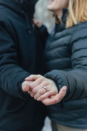 A picture of a man holding a woman's hand and the engagement ring.
