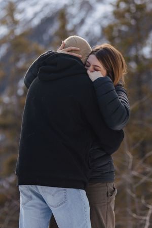 A couple embraces and are dancing in a winter mountain background.