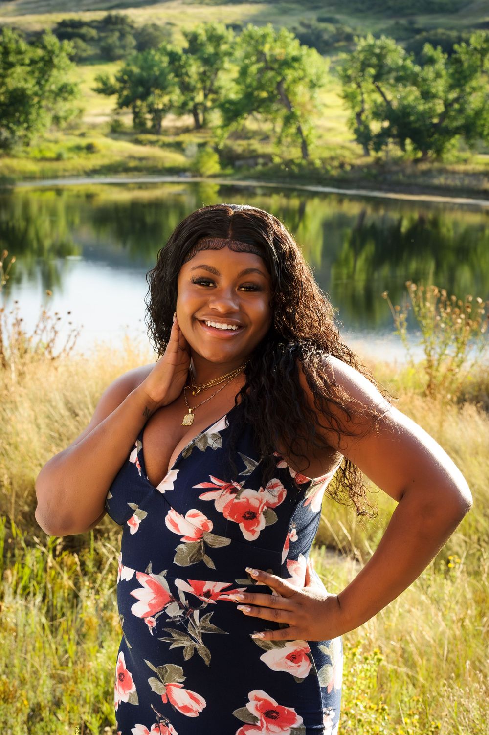 Summer portrait by a lake featuring a floral dress against natural landscape.