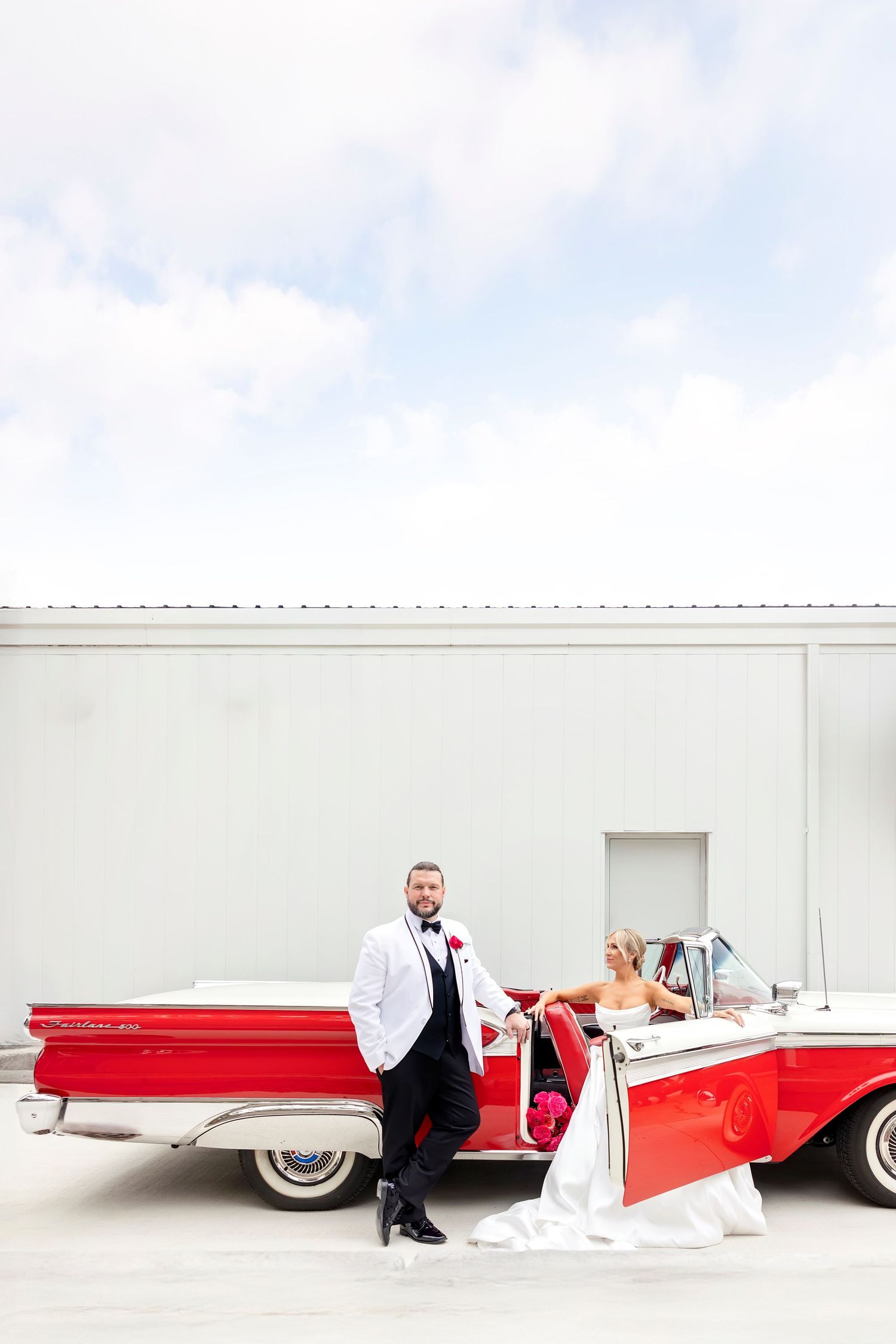 Newly married couple posing in their classic red and white getaway car in Clear Lake, Iowa wedding.