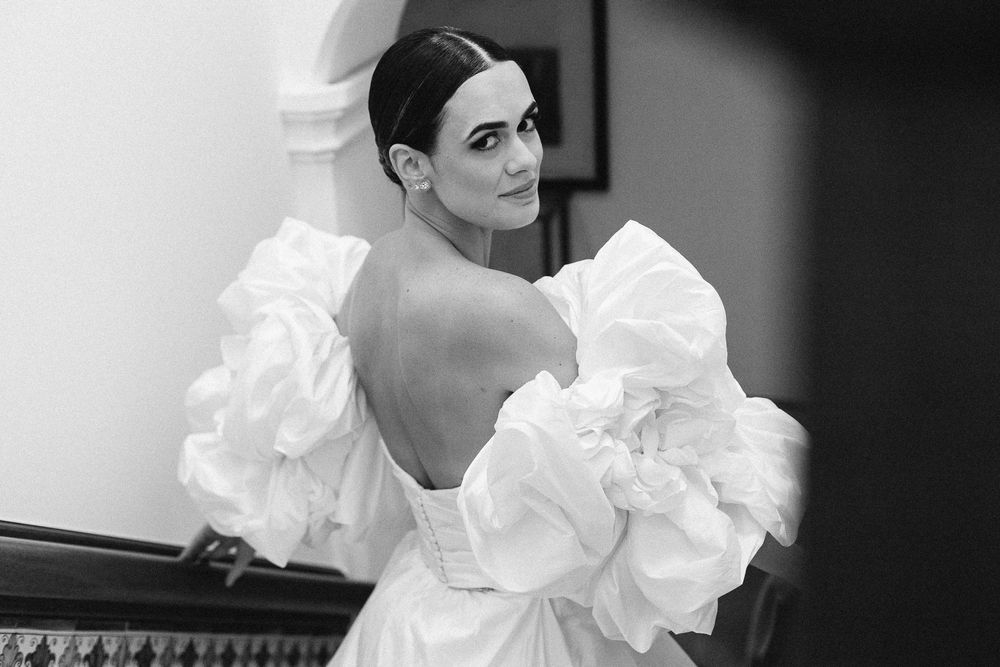 Black and white portrait showing dramatic puff sleeve wedding gown with open back.