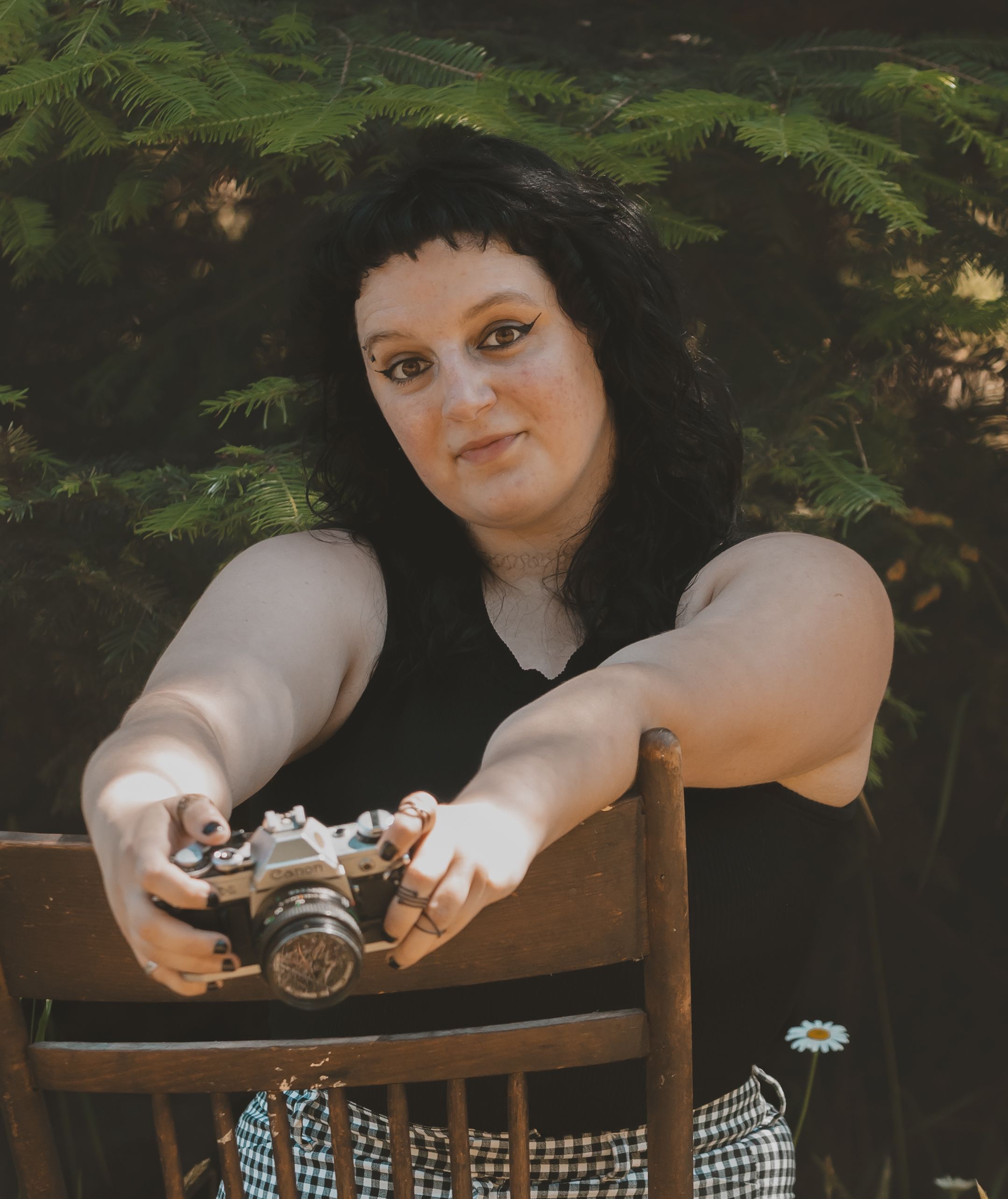 A woman is sitting on a chair that is backwards holding a camera in front of her