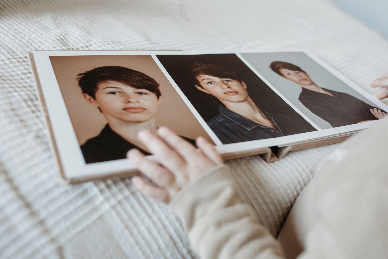 Een fotoalbum (fotoboek) die open ligt. Een kinderhand bladert door het boek en gaat met haar handje over een van de foto's.