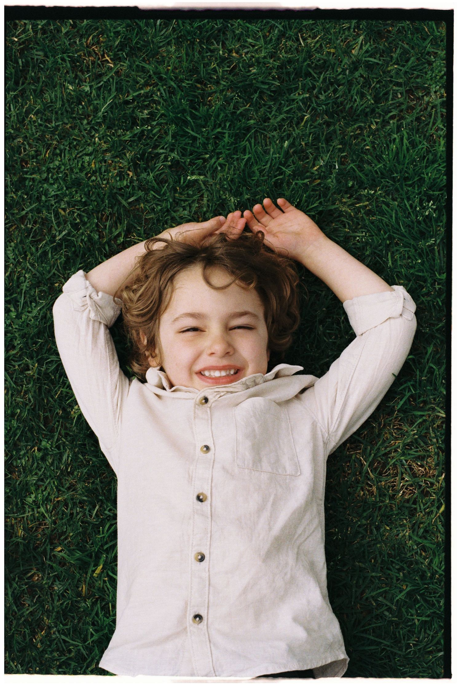 boy lying on the grass smiling captured on 35mm film