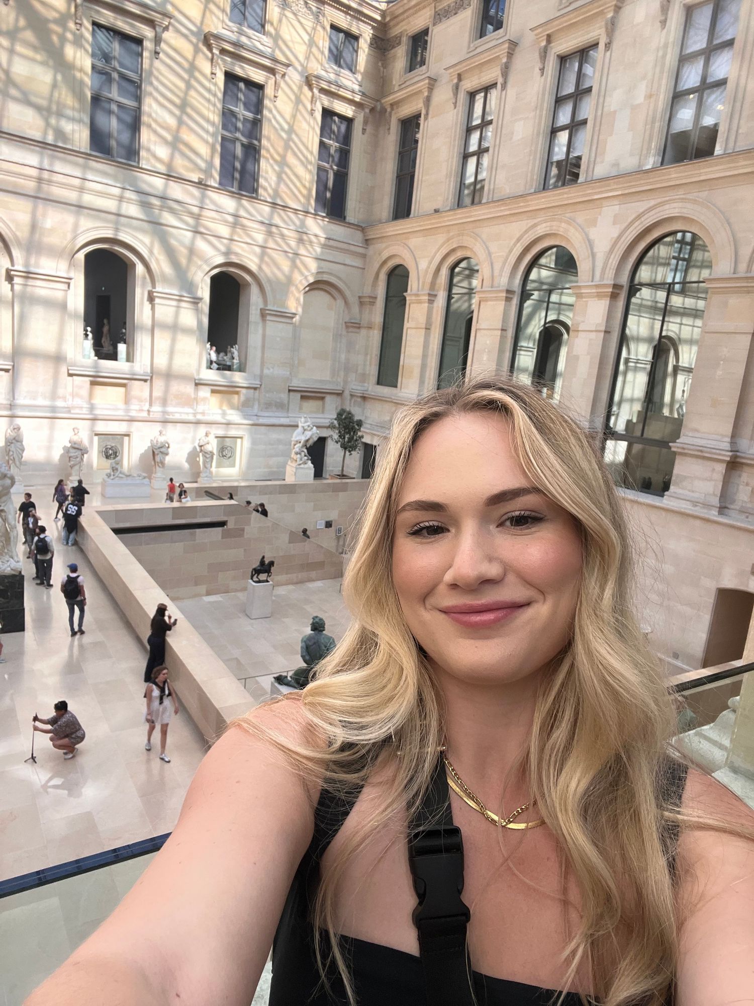Blonde woman taking a selfie inside the Louvre Museum in Paris, France.