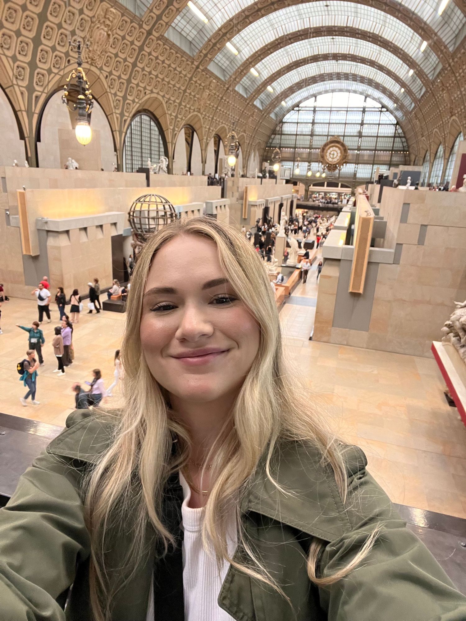Blonde woman taking a selfie inside the grand Musée d'Orsay in Paris, France.