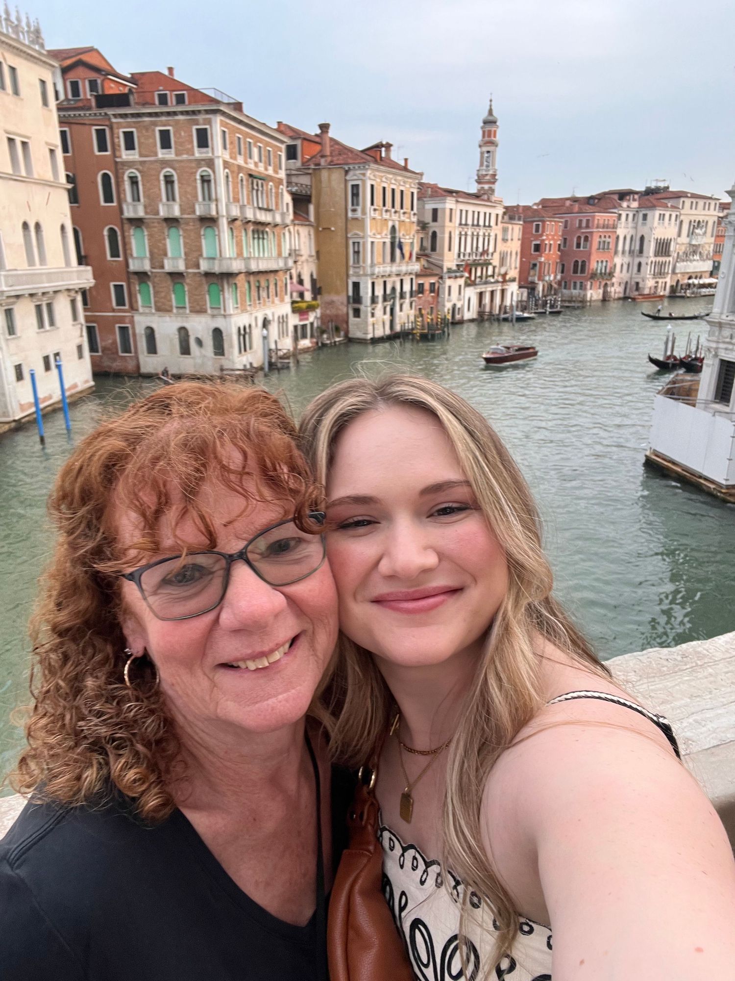 Two women take a selfie on the Rialto Bridge over the Grand Canal in Venice, Italy.