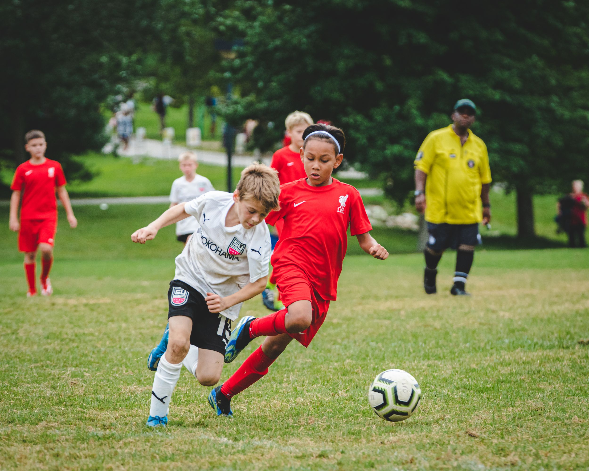 Two youth soccer players compete for ball possession during an outdoor summer match.