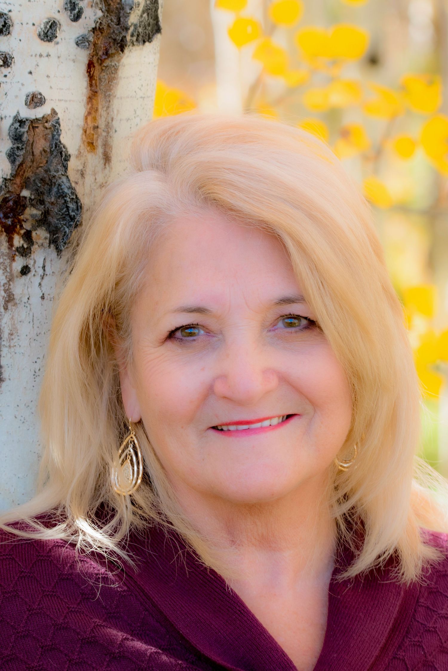 Portrait against birch tree with yellow autumn foliage in background.