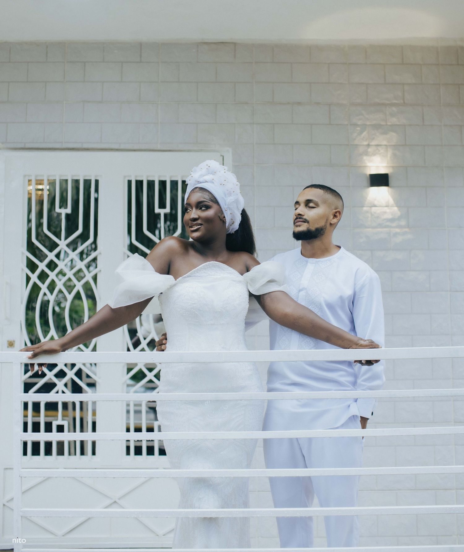 Happy couple sharing a moment on white balcony with geometric wall design.