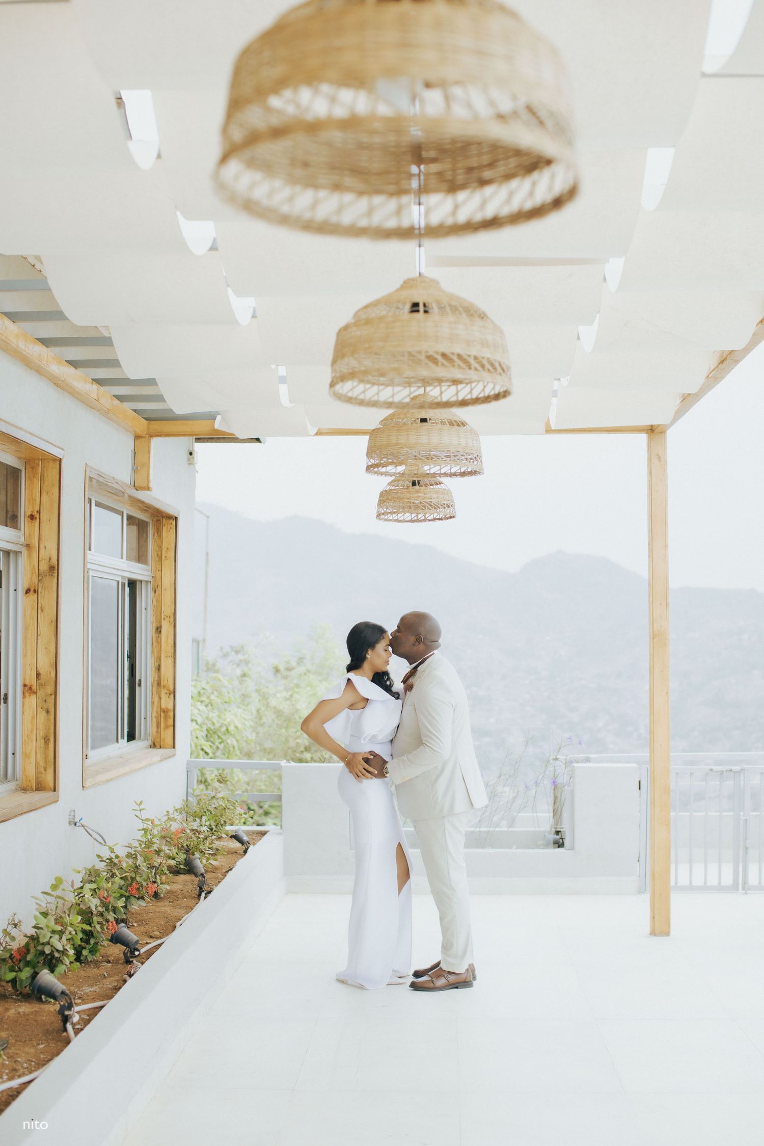 A romantic moment under woven pendant lights with mountain views in the background.