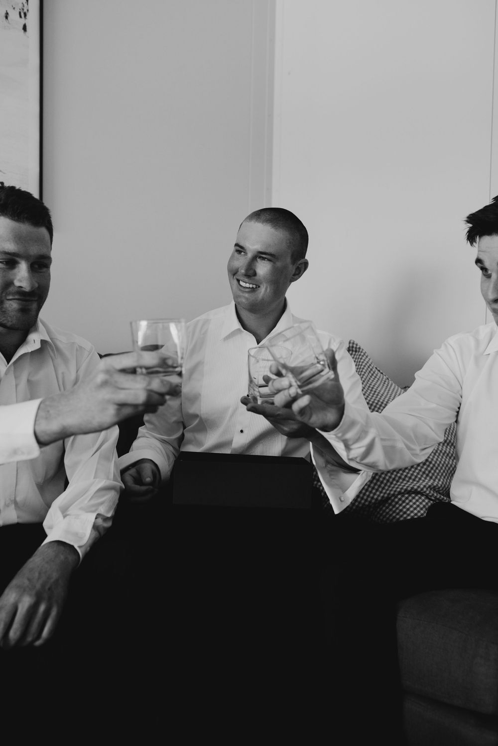 Black and white photo of groom and groomsmen sharing a celebratory toast before the wedding ceremony.