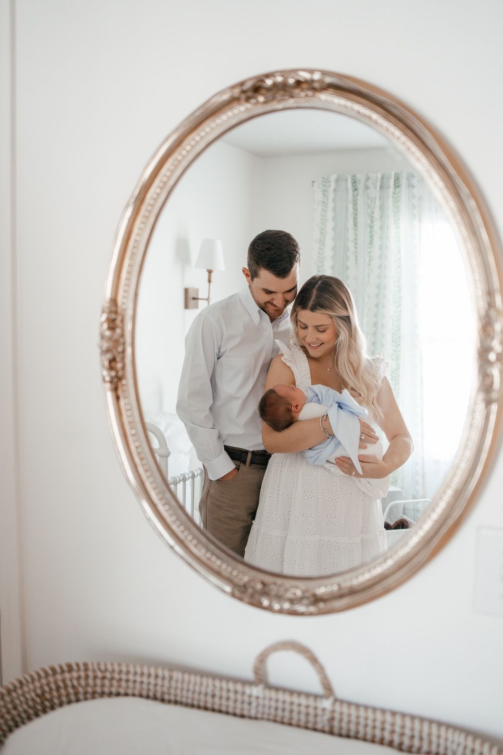 Mom and dad holding their baby in the reflection of them in a mirror