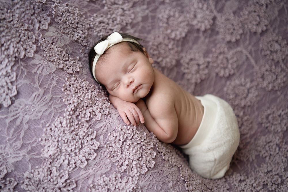 Newborn girl on a purple lace blanket