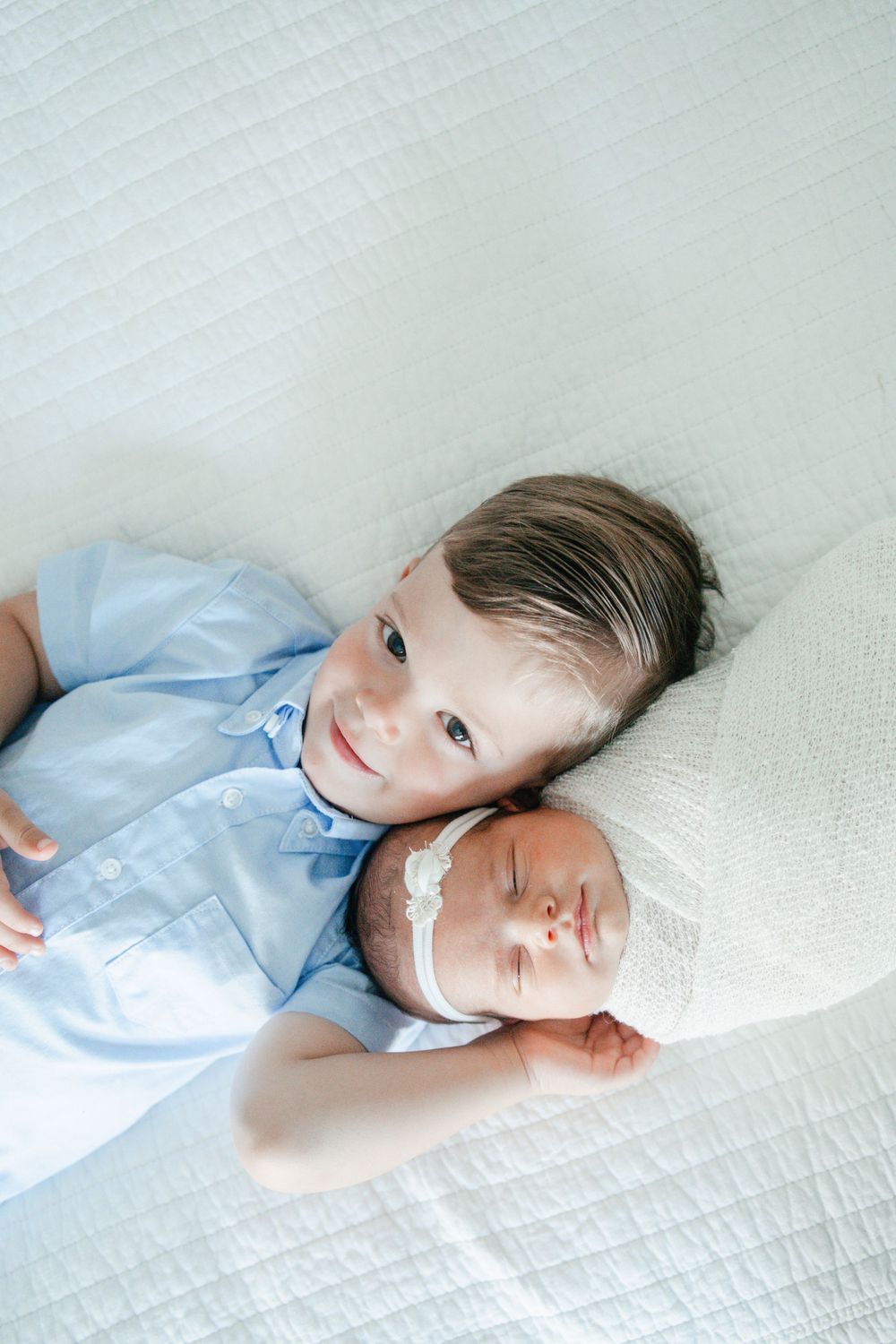 Big brother and newborn baby sitter laying down