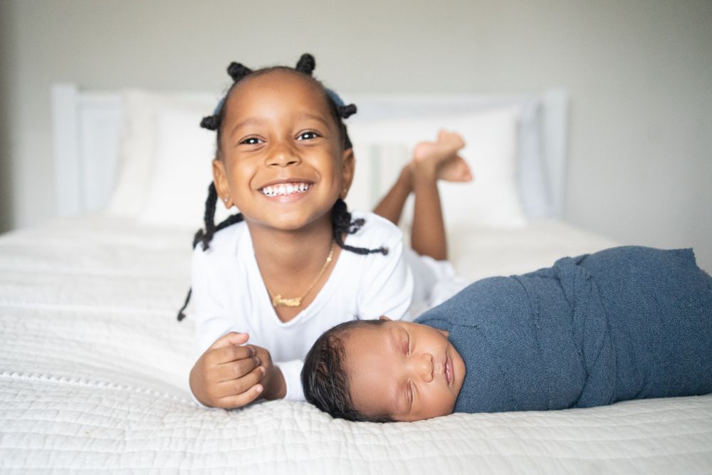 Older sister with her newborn baby brother in front of her