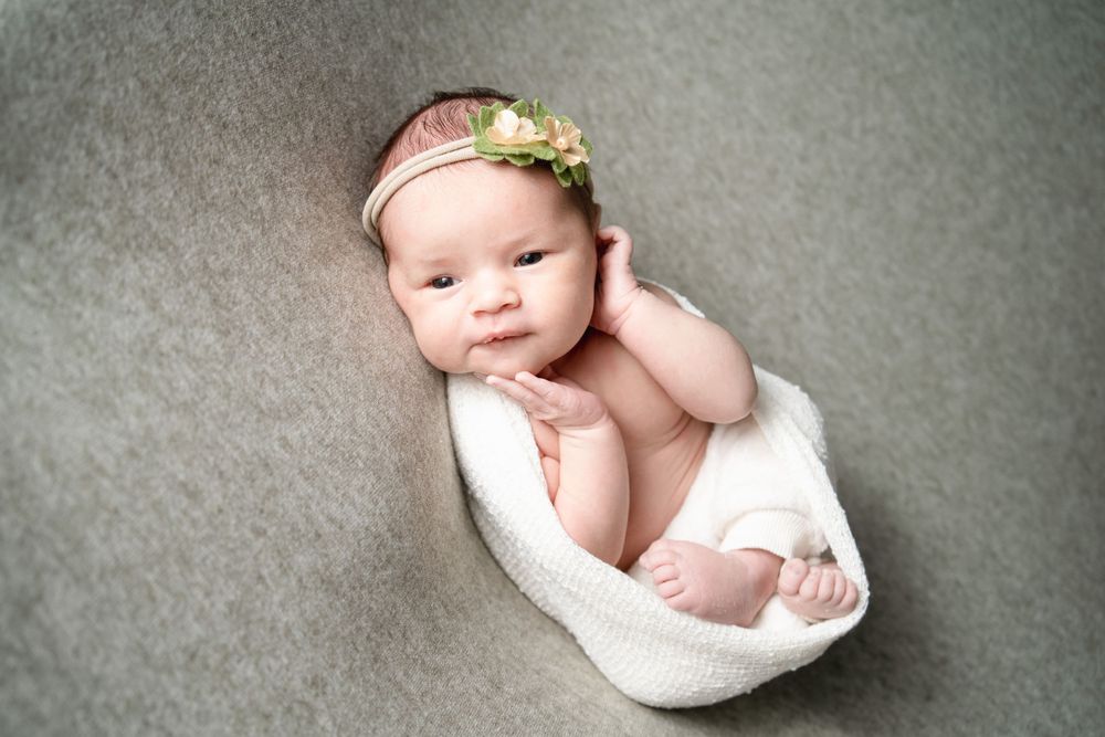 Newborn baby girl in a cute headband and hands by her head