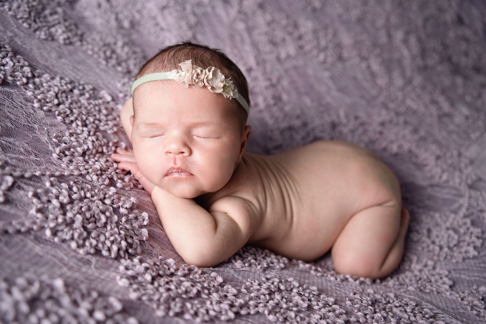 Newborn baby girl laying on her stomach w