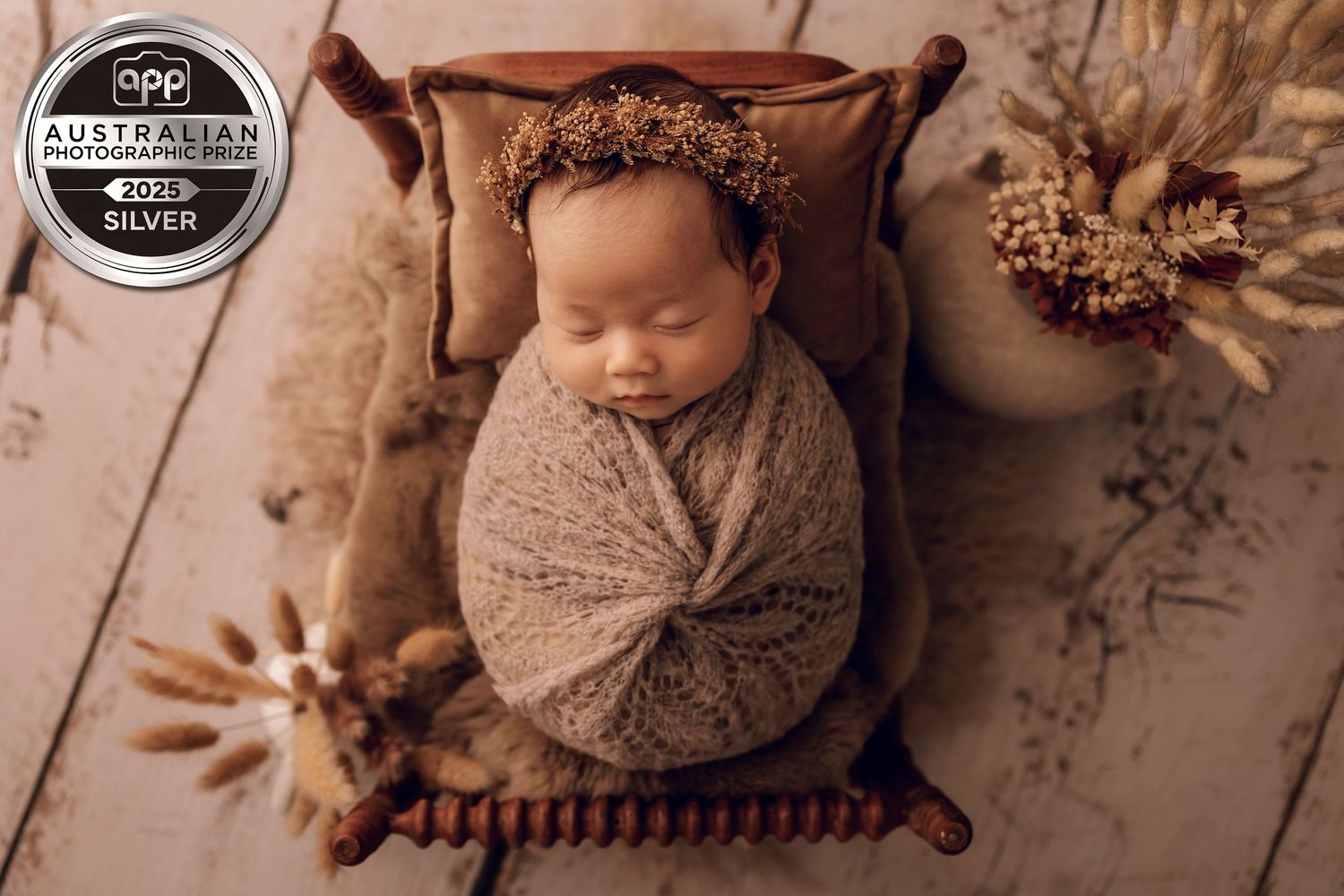 Sleeping newborn baby wearing beige knit romper lies peacefully in rustic wooden bowl. Professional newborn photographer, Townsville, QLD