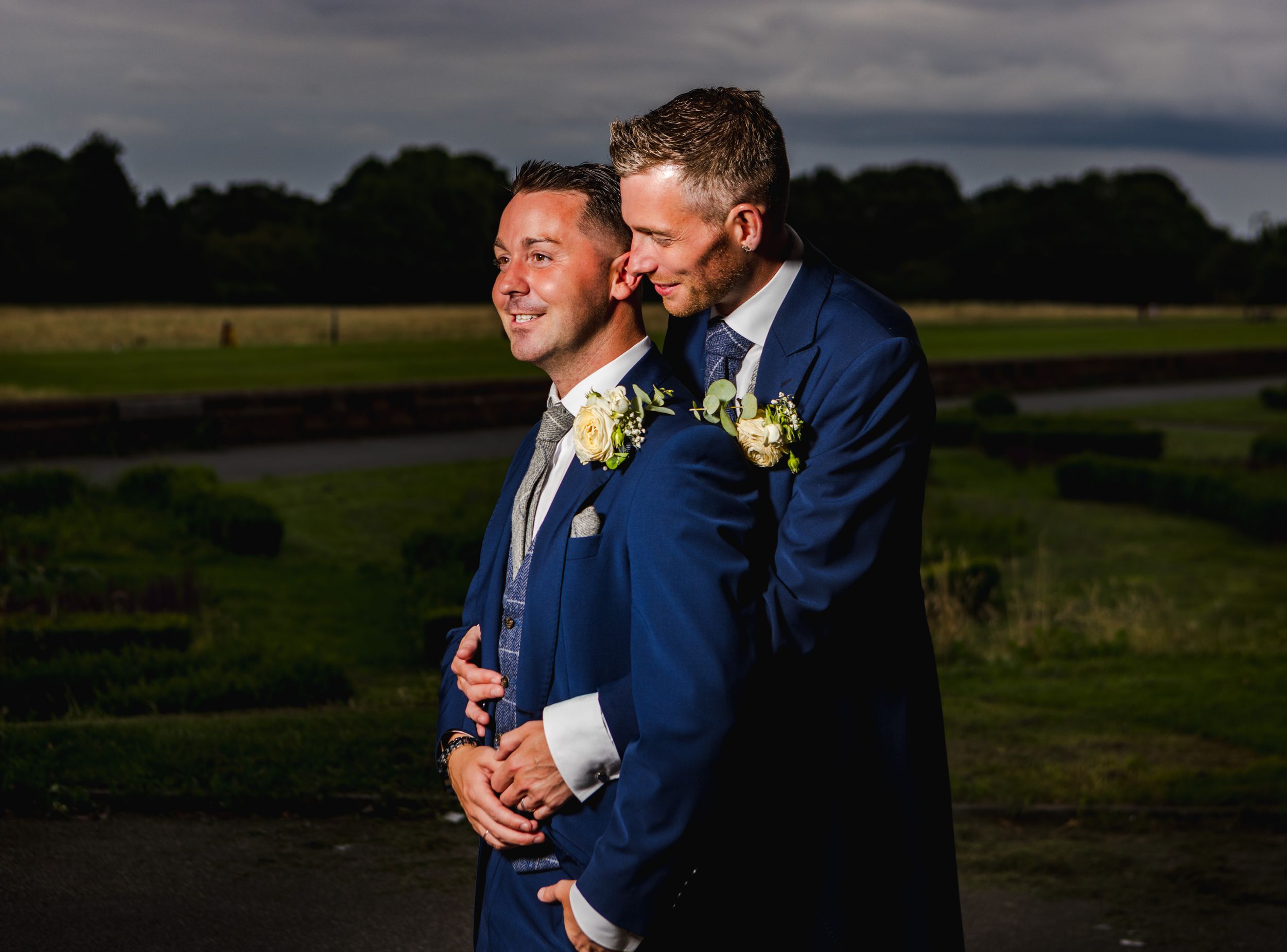 Romantic outdoor wedding photos taken at dusk show couple embracing against dramatic cloudy sky.