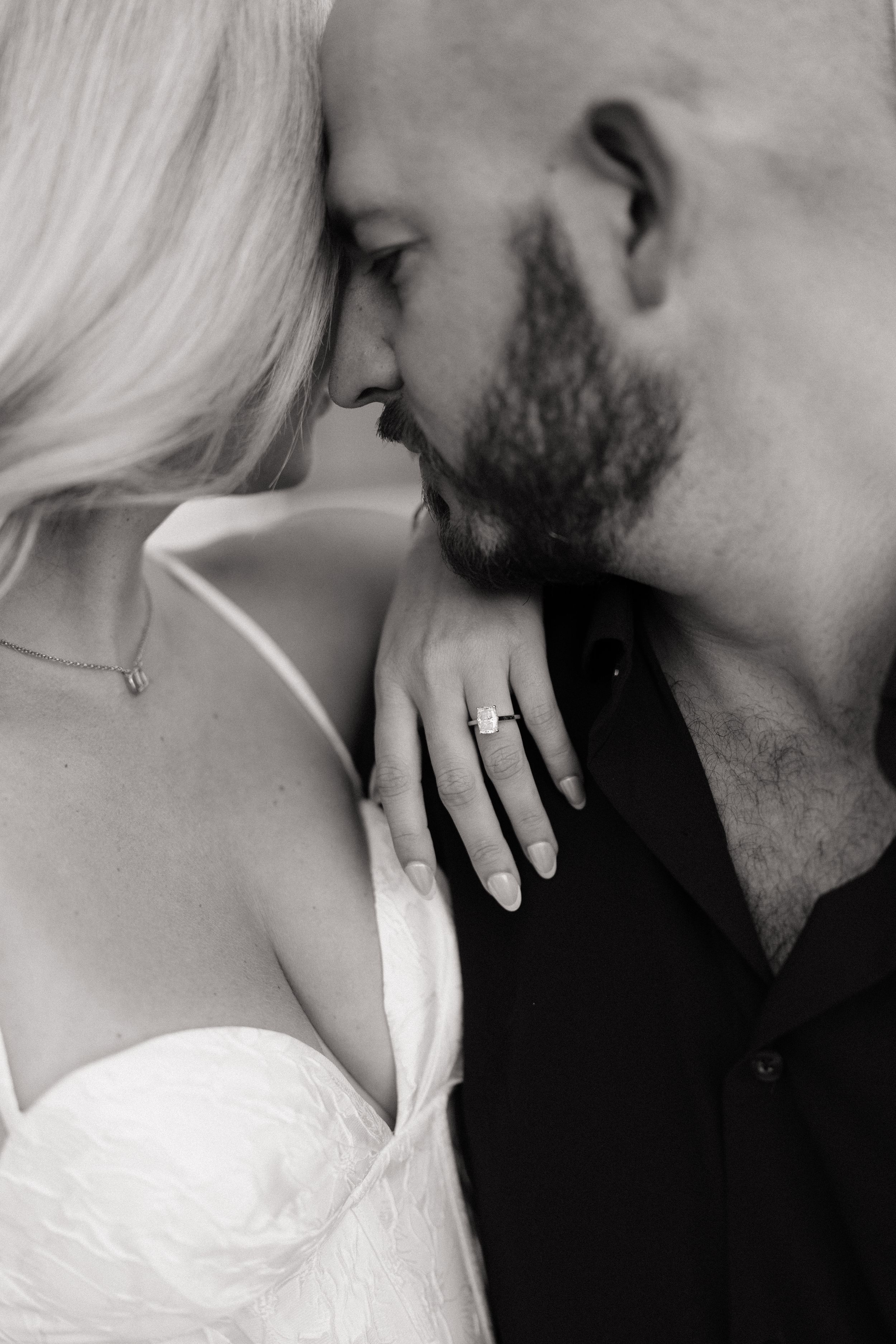 Intimate black and white close-up of couple nearly kissing, engagement ring visible on bride's hand. Fresno California Wedding Photographer