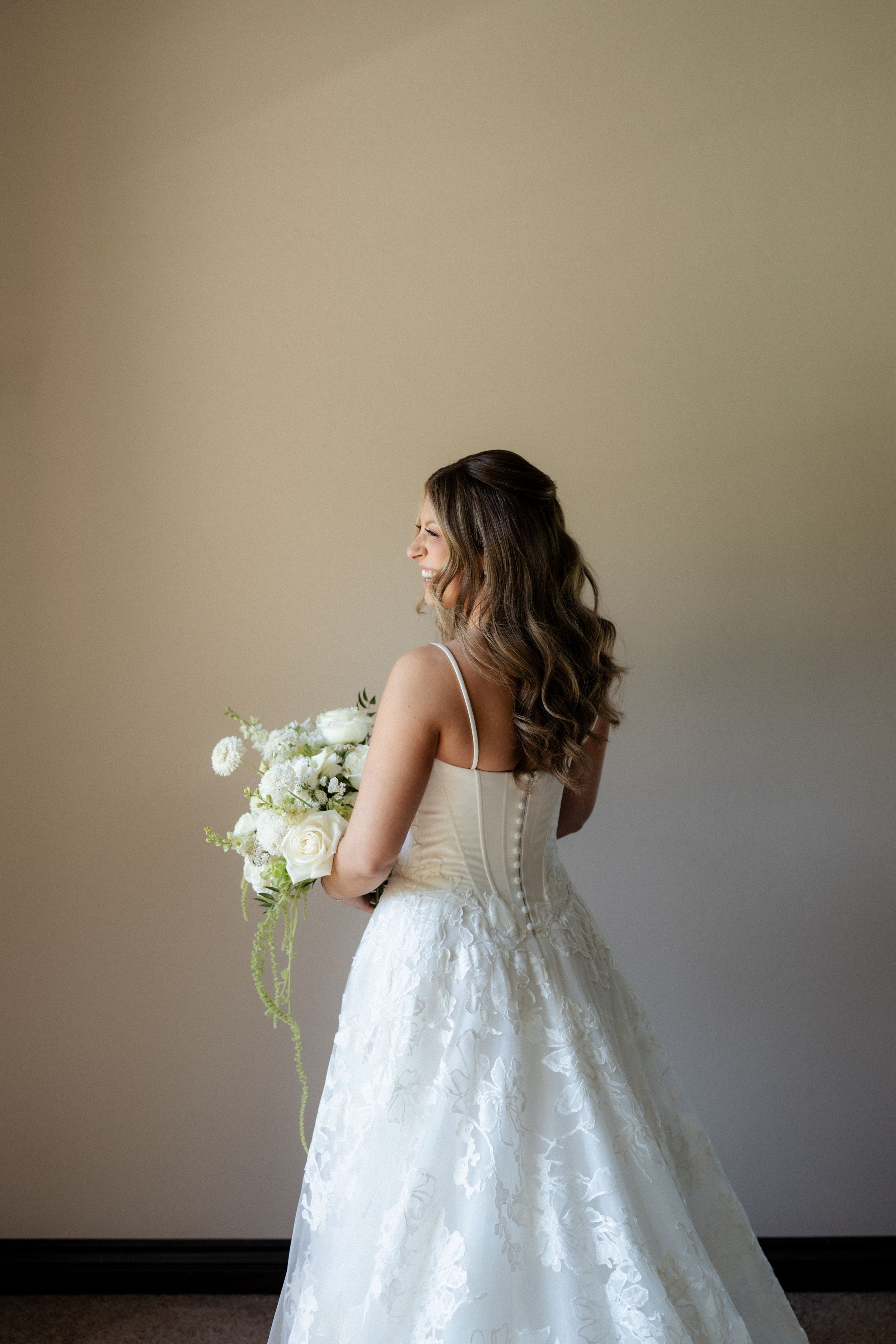Bride in white lace gown holding bouquet of white flowers. Fresno California Wedding Photographer and Videographer