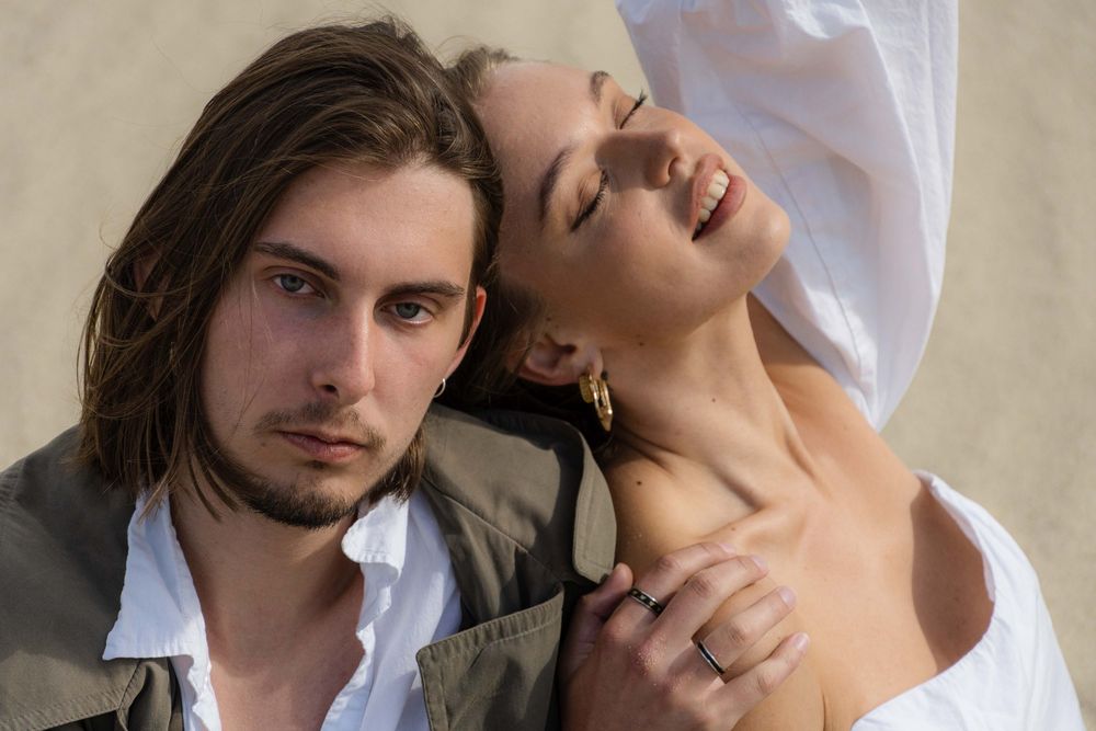 A woman is leaning on the man at the seaside.