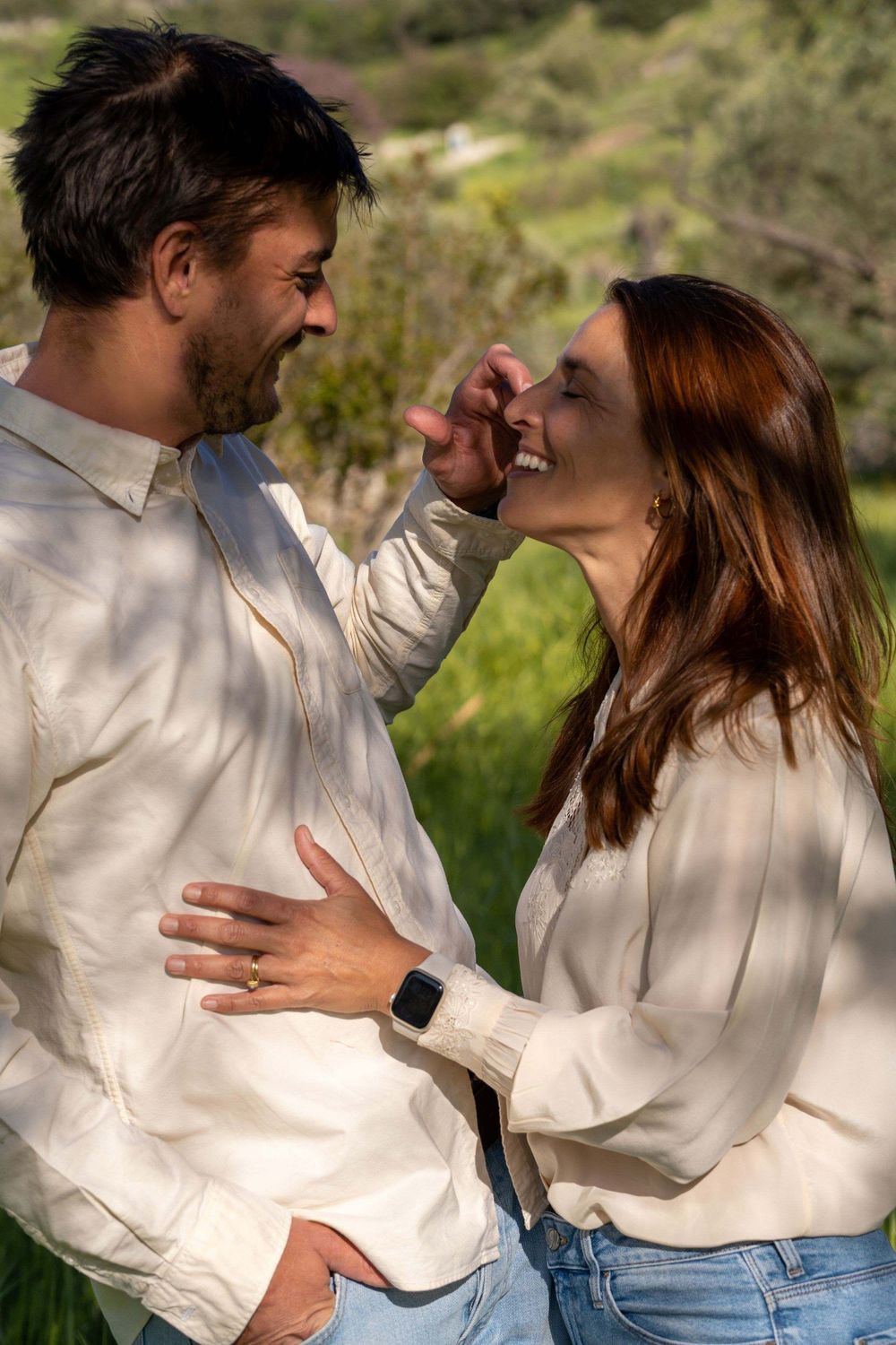 A man and woman stand smiling towards each other.
