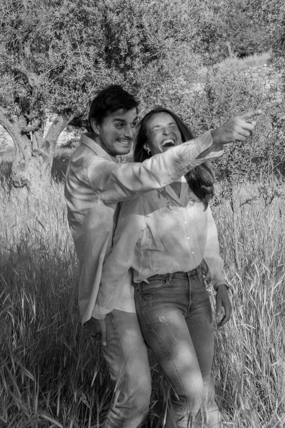 A man hugs a woman and a woman laughs.