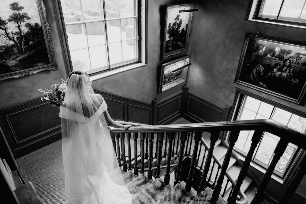 Pauntley Court photography on staircase as bride walks to first look