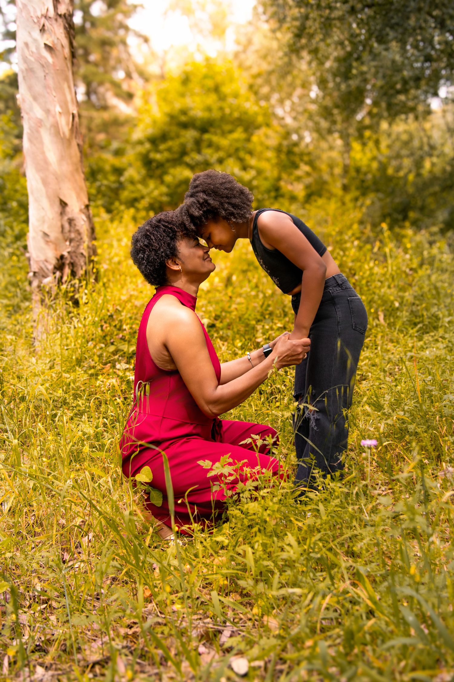 A romantic proposal scene in a sunlit meadow with golden wildflowers and a birch tree in the background.