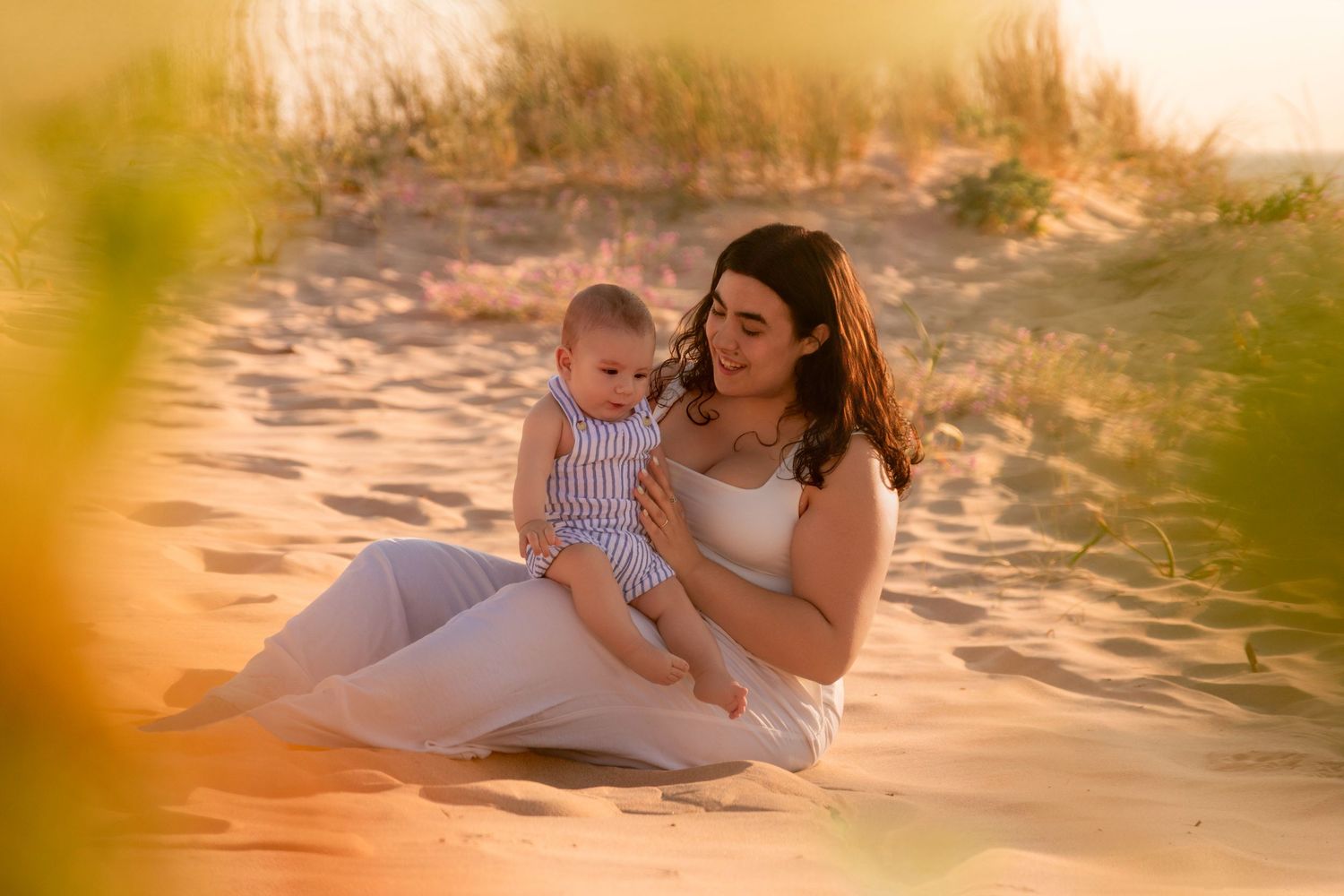 Family poses together on beach during golden hour sunset photoshoot.